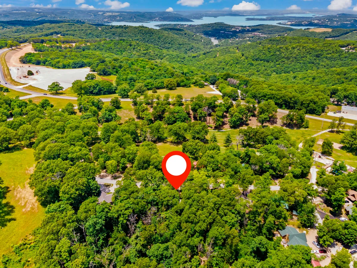 A scenic view of lush green trees, rolling hills, and a distant water body, showcasing the picturesque natural surroundings of the Ozarks. The landscape invites exploration, outdoor adventures, and appreciation of the area's tranquility.